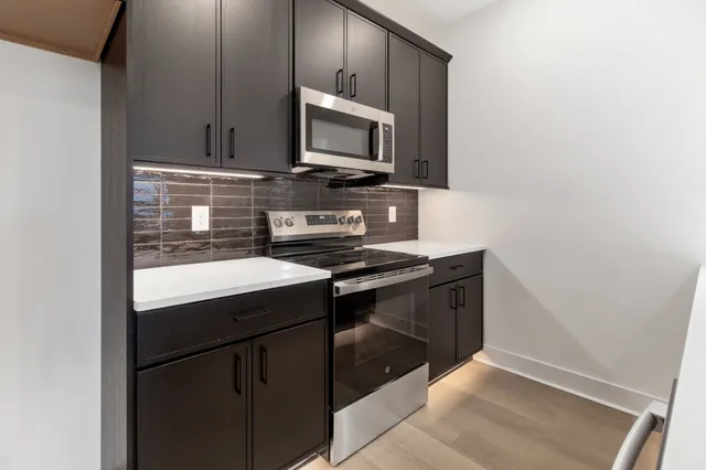 a kitchen with stainless steel appliances a stove microwave and sink