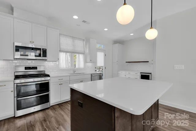 a kitchen with cabinets appliances and wooden floor