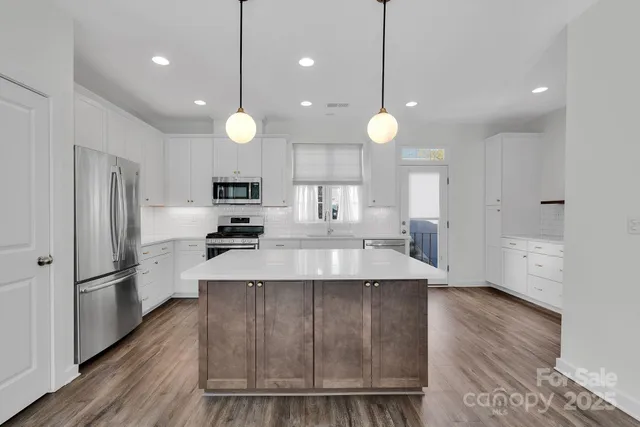 an open kitchen with wooden floor and stainless steel appliances