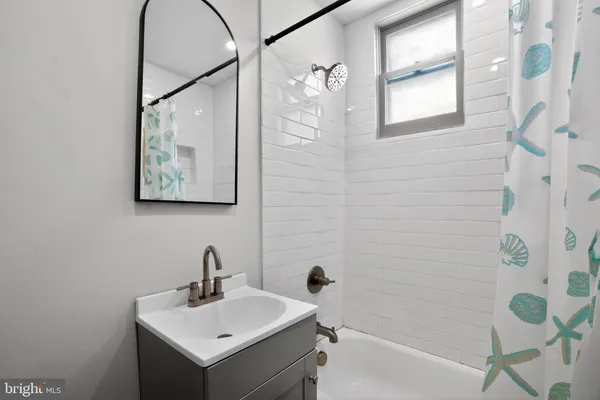 a bathroom with a sink and mirror with bathtub
