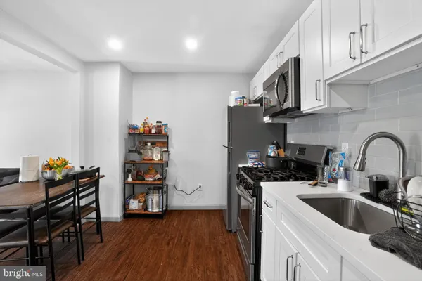 a kitchen with stainless steel appliances a sink a stove and wooden floors