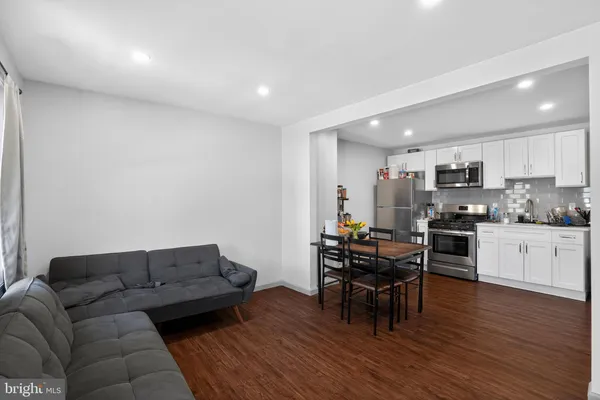 a living room with furniture and a dining table with wooden floor