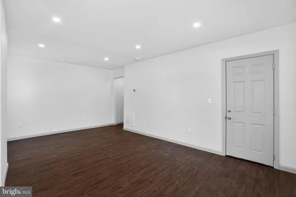 a view of an empty room with wooden floor and closet