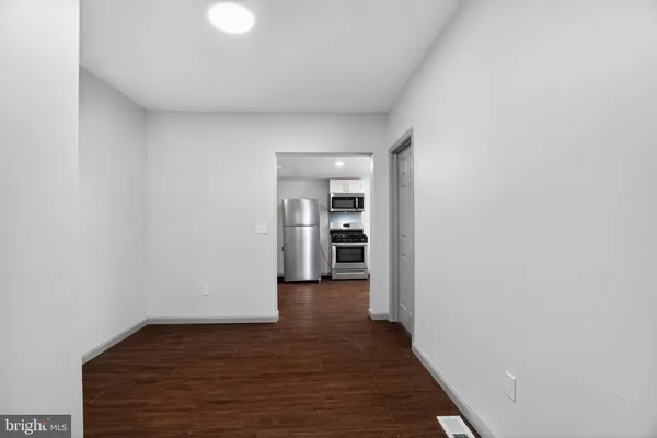 a view of a hallway with wooden floor and a bathroom