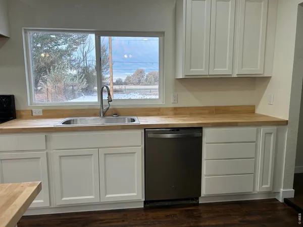 a kitchen with granite countertop white cabinets and a wooden floor
