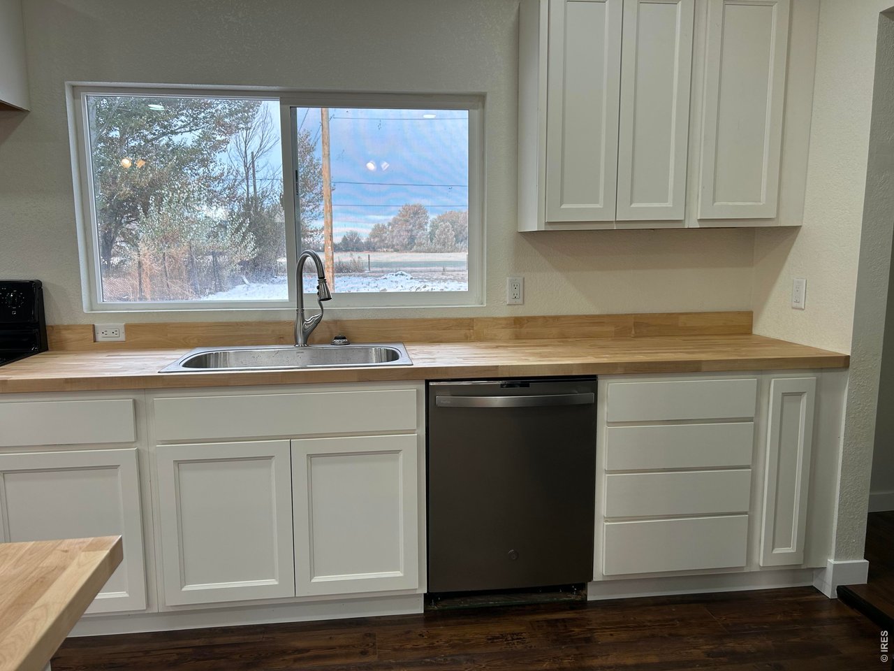 809 Warren Street Weldona, CO 80653 - Photo 5 of 19 a kitchen with granite countertop white cabinets and a wooden floor