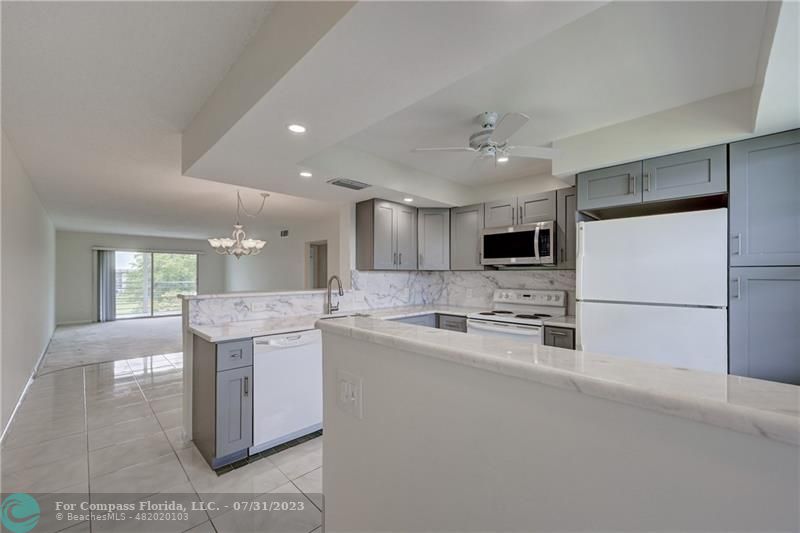 a kitchen with stainless steel appliances granite countertop a sink and a stove top oven with white cabinets