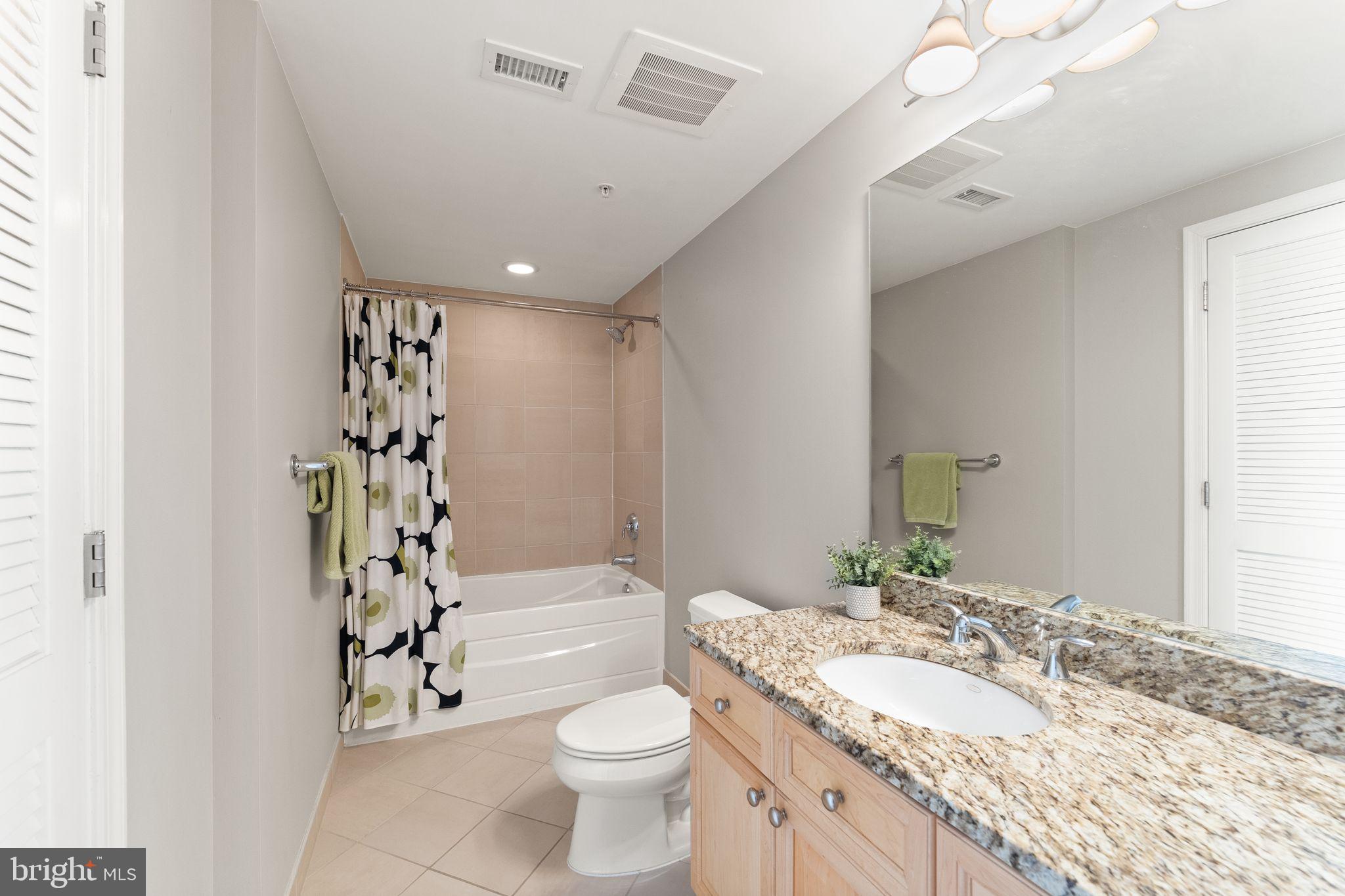 11990 Market Street, Unit 701 Reston, VA 20190 - Photo 24 of 93 a bathroom with a granite countertop sink a toilet a mirror a vanity and shower