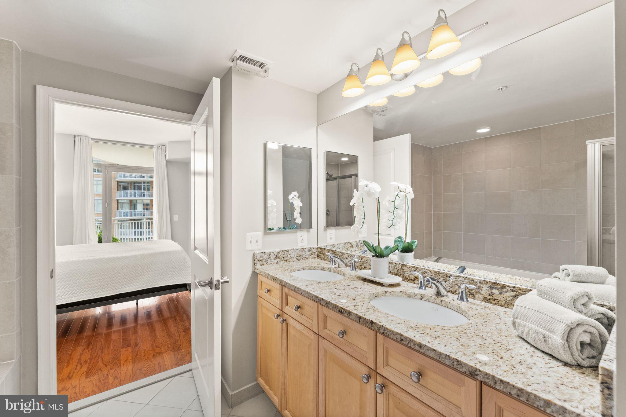 11990 Market Street, Unit 701 Reston, VA 20190 - Photo 38 of 93 a bathroom with a granite countertop sink a mirror and a shower