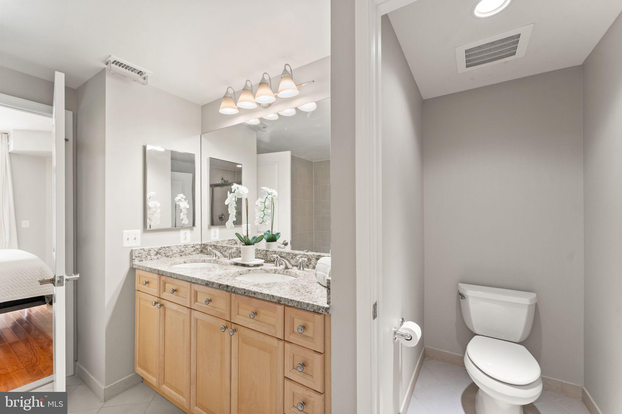 11990 Market Street, Unit 701 Reston, VA 20190 - Photo 40 of 93 a bathroom with a granite countertop toilet sink and mirror