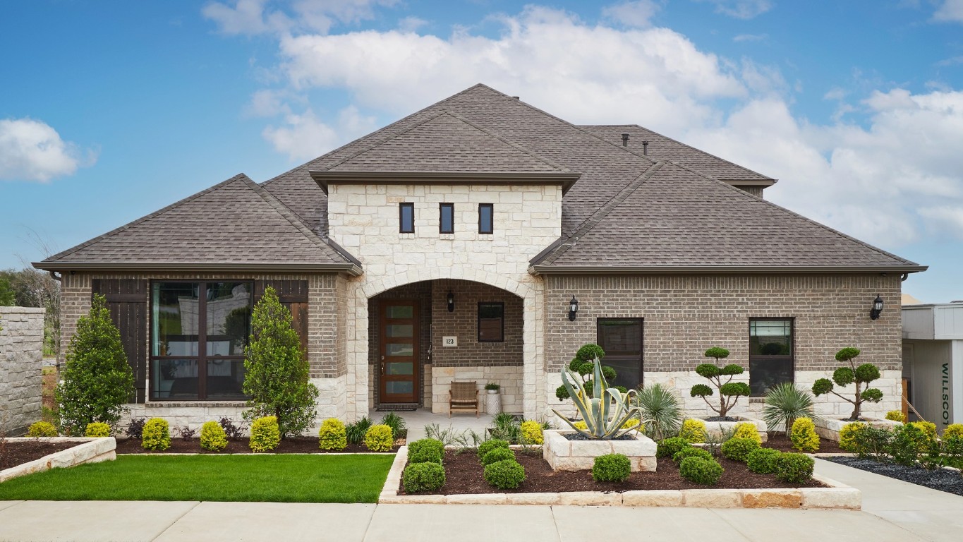 French country home with stone siding, a shingled roof, and brick siding