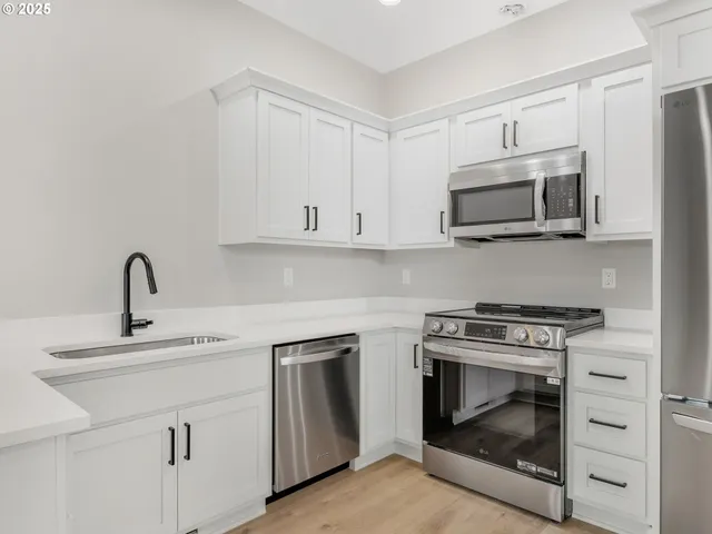 a kitchen with white cabinets and stainless steel appliances