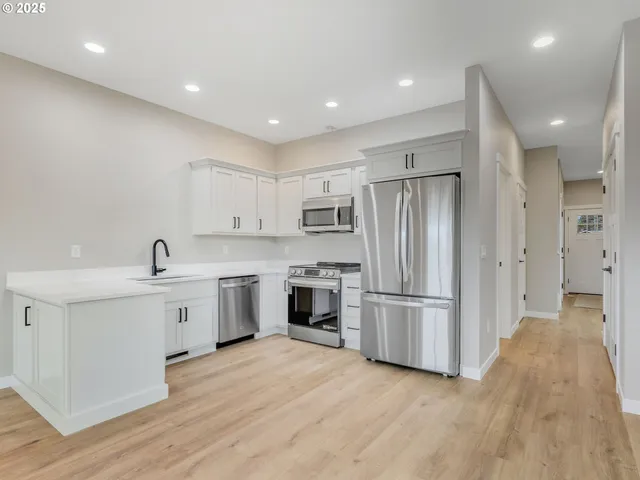 a large kitchen with stainless steel appliances granite countertop a refrigerator and a sink