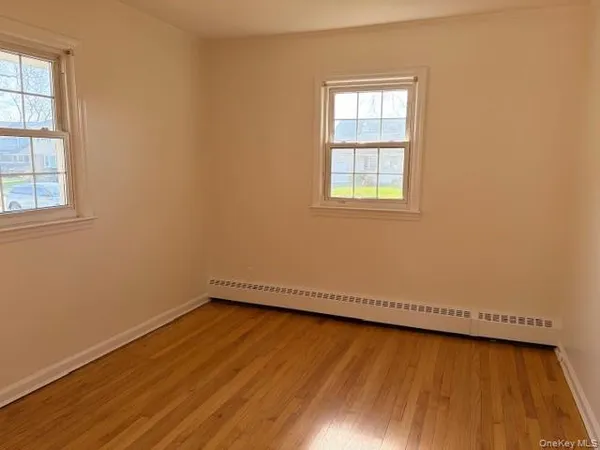 an empty room with a hardwood and windows