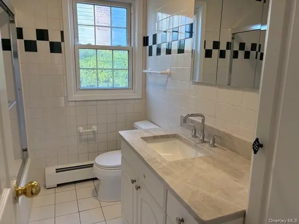 a bathroom with a granite countertop sink a toilet a mirror and shower