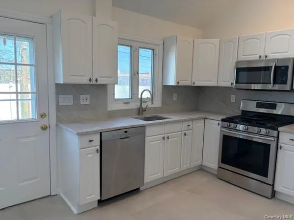 a kitchen with stainless steel appliances granite countertop white cabinets granite counter tops and a window