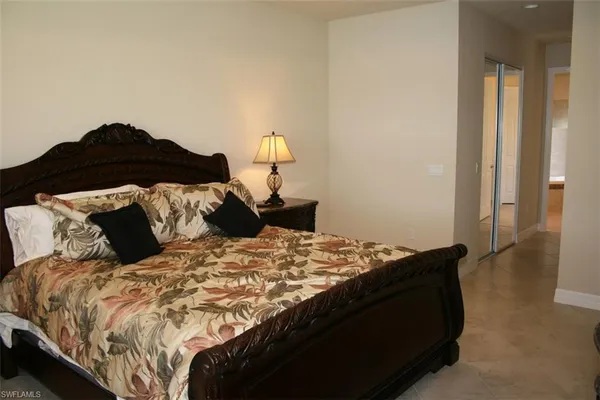 a bed sitting in a bedroom next to a window and a lamp