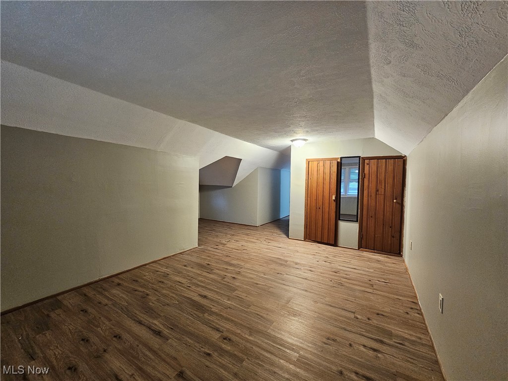 13514 Granger Road Cleveland, OH 44125 - Photo 15 of 23 Bonus room with a textured ceiling, lofted ceiling, and hardwood / wood-style flooring