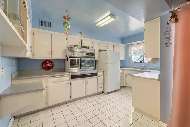 a bathroom with a sink a refrigerator and a window