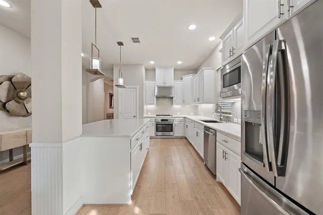 a large kitchen with stainless steel appliances lots of counter space and a sink