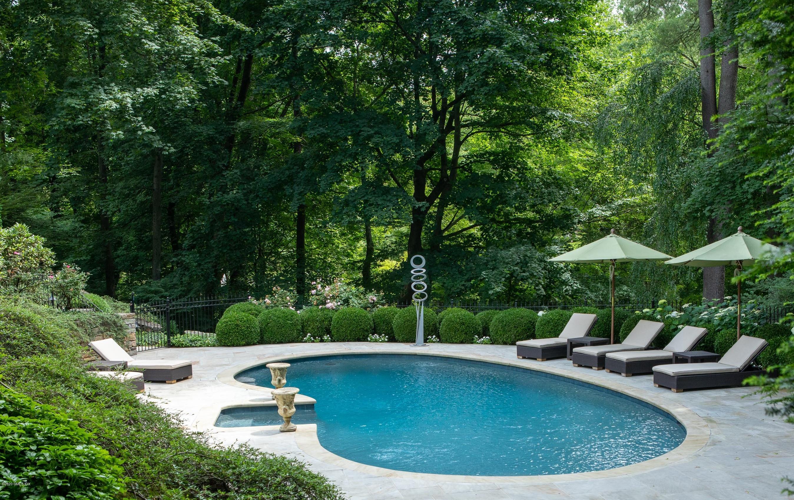 23 Boulder Brook Road Greenwich, CT 06830 - Photo 22 of 27 a view of a swimming pool with lawn chairs under an umbrella