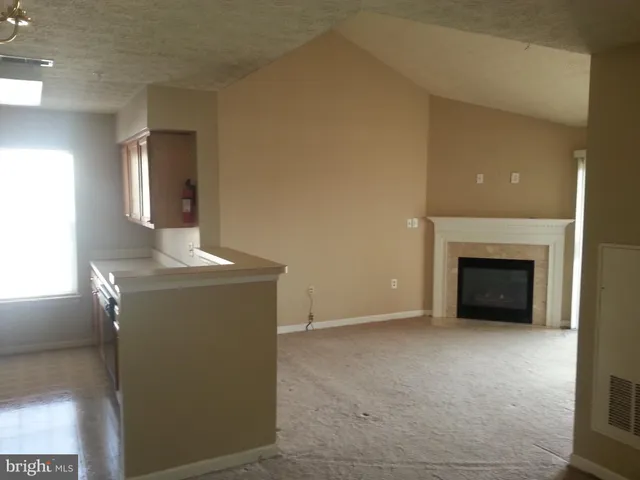 a view of an empty room with a fireplace and a window