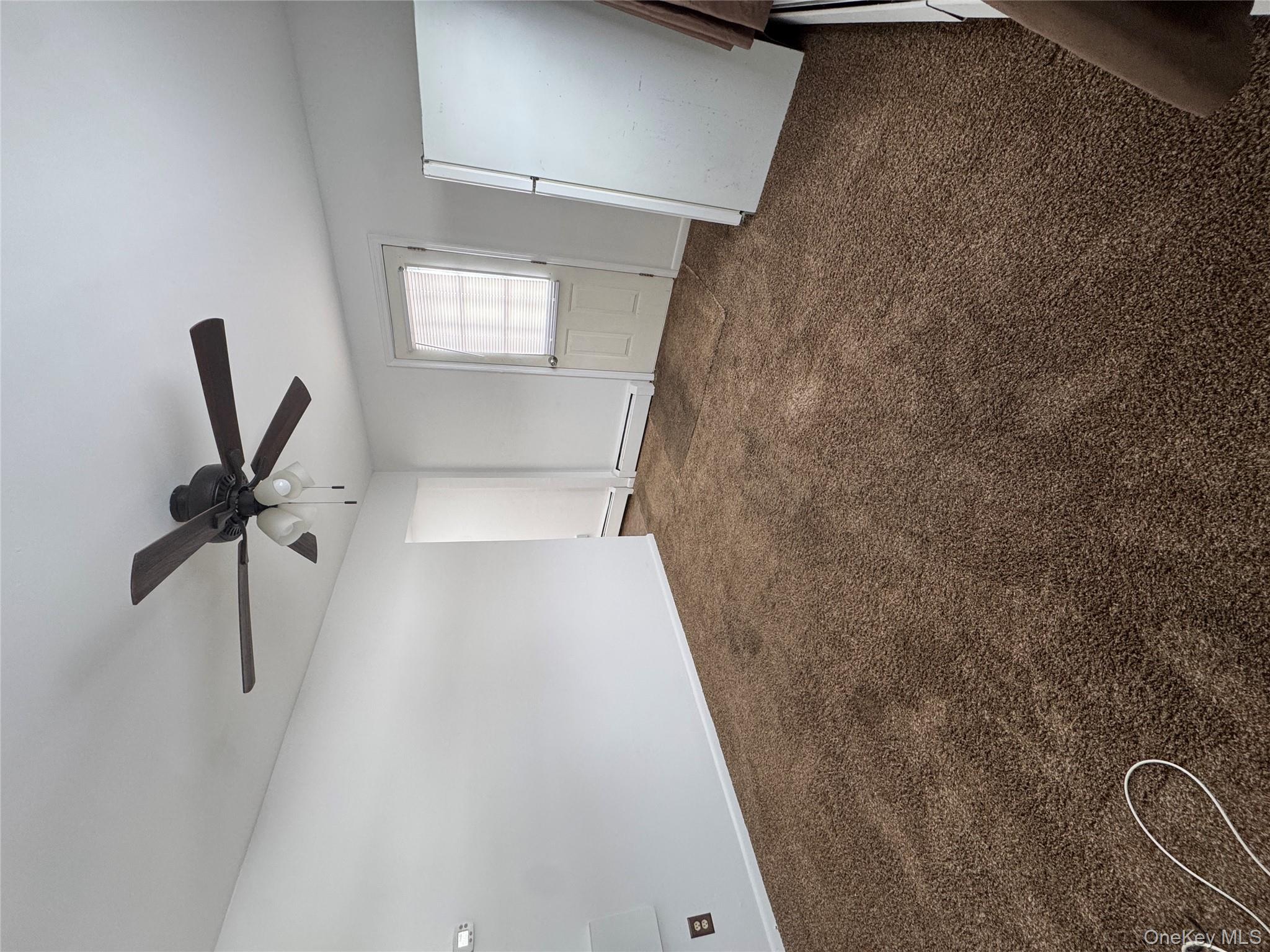 523 Fostertown Road Newburgh, NY 12550 - Photo 3 of 15 Unfurnished room featuring dark carpet, a ceiling fan, and a baseboard radiator