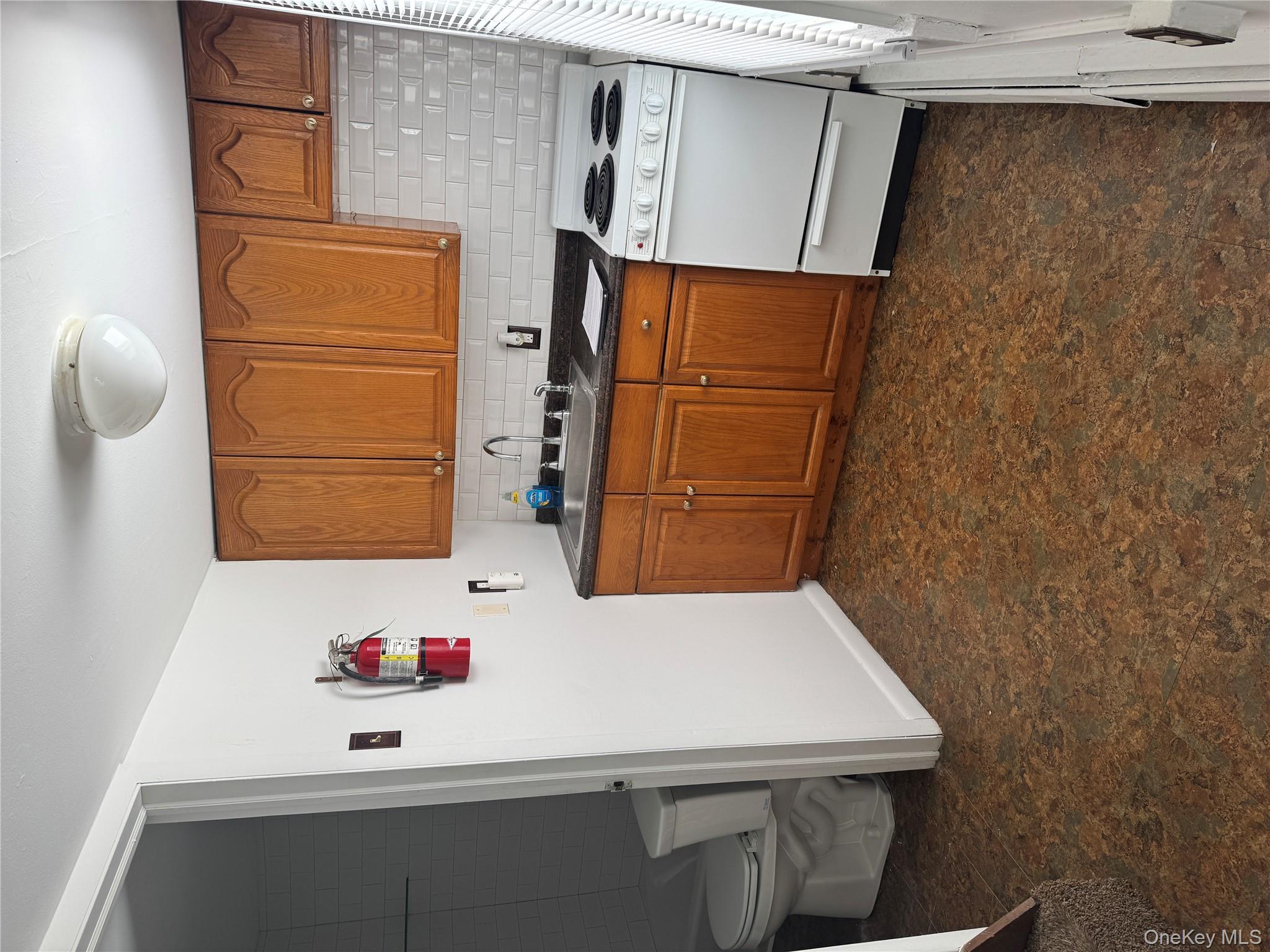 523 Fostertown Road Newburgh, NY 12550 - Photo 5 of 15 Kitchen with range, brown cabinetry, dark countertops, decorative backsplash, and dark floors