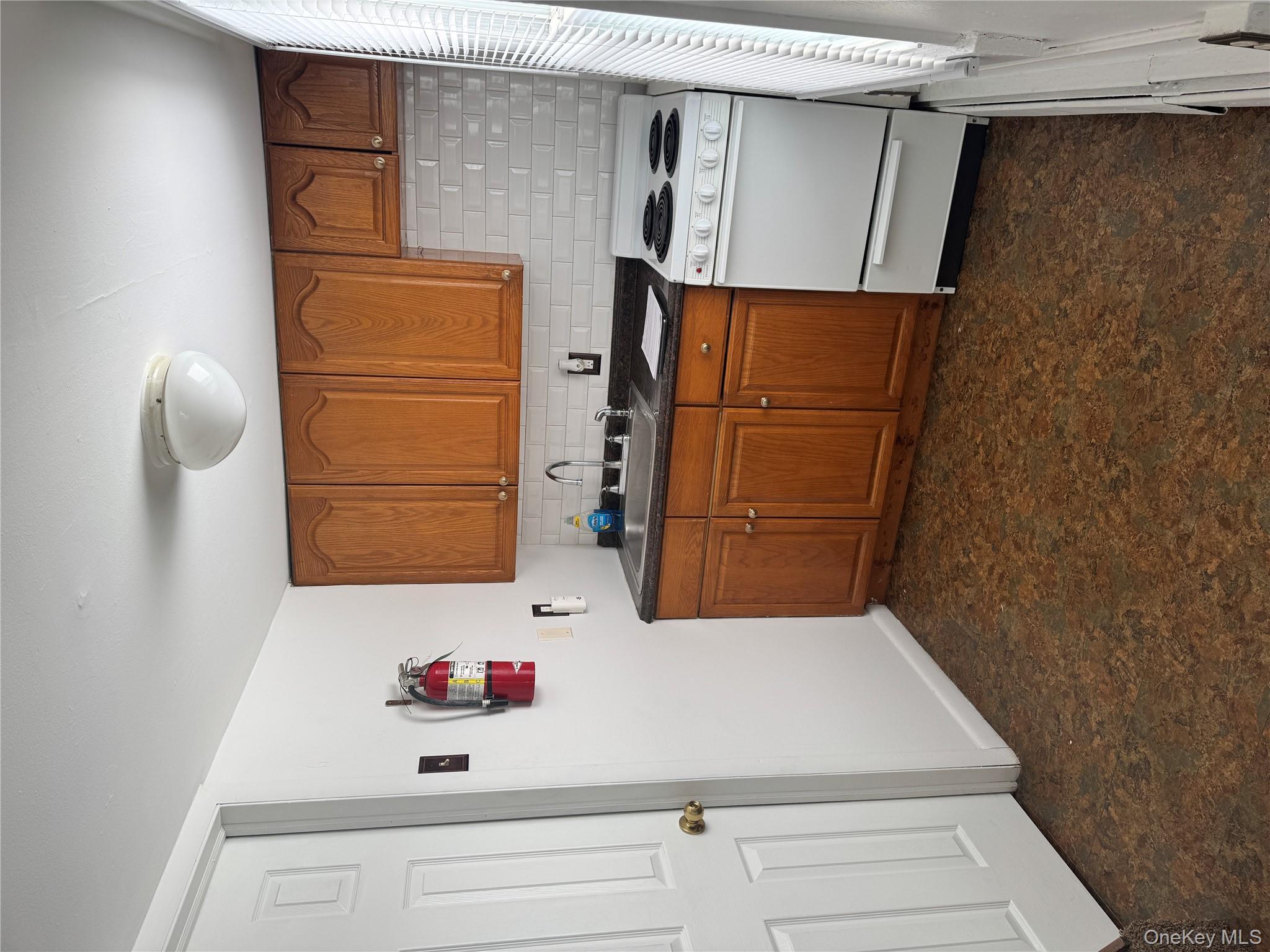 523 Fostertown Road Newburgh, NY 12550 - Photo 6 of 15 Kitchen featuring range, brown cabinetry, dark countertops, tasteful backsplash, and baseboard heating
