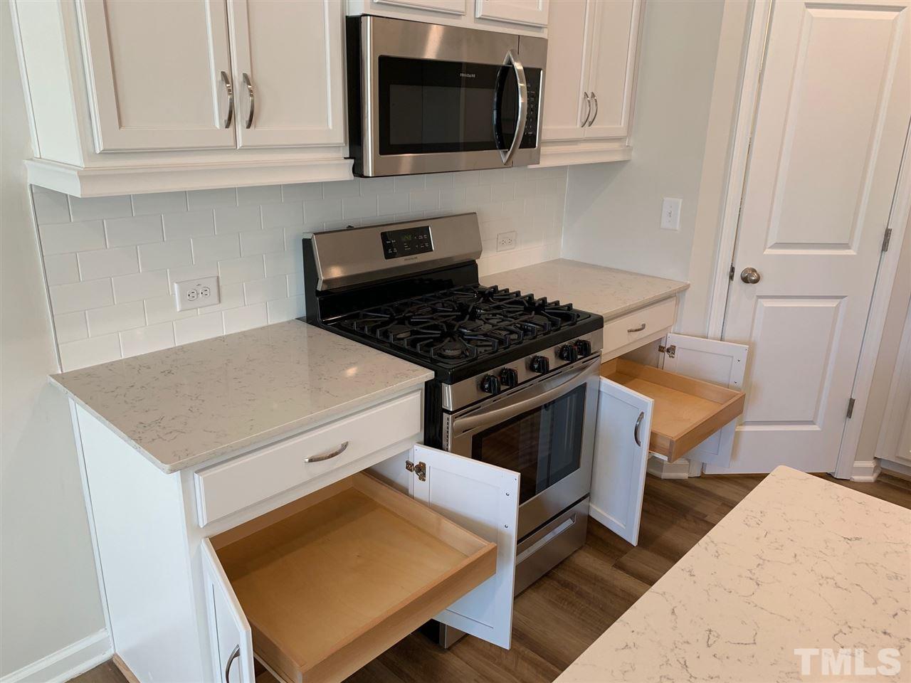 6108 Beale Loop, Unit 101 Raleigh, NC 27616 - Photo 6 of 30 a kitchen with stainless steel appliances a stove a microwave a refrigerator and cabinets