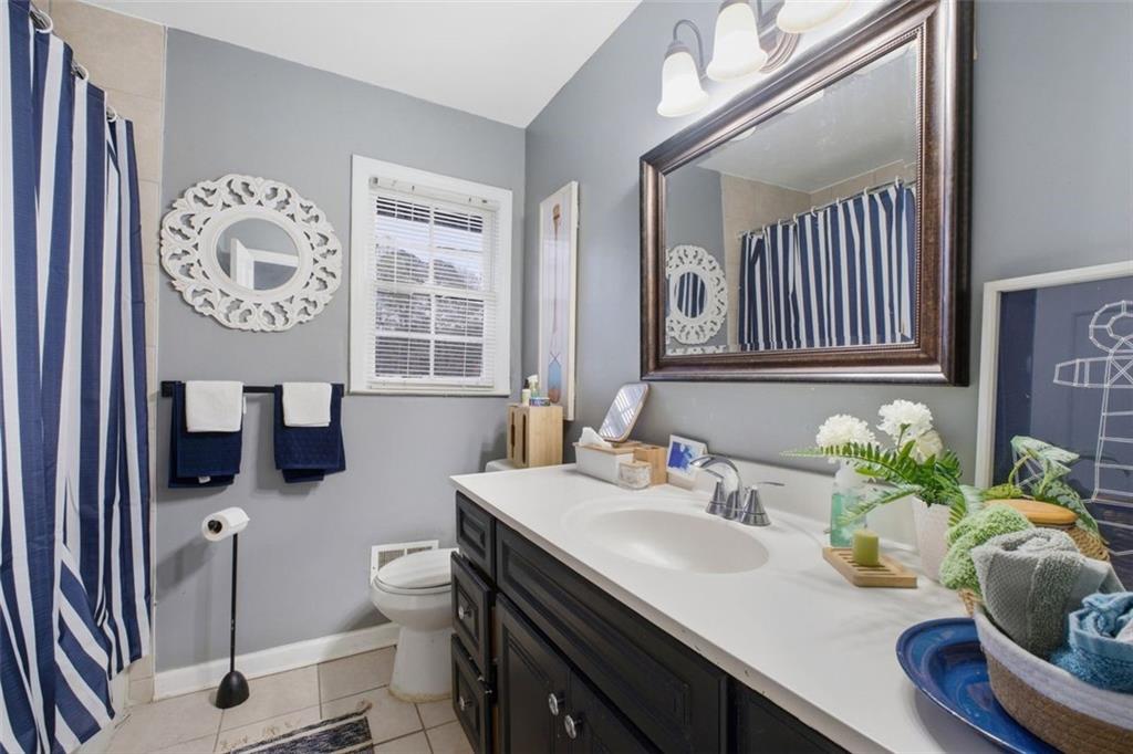957 Rowland Road Stone Mountain, GA 30083 - Photo 23 of 36 a bathroom with a granite countertop toilet sink and mirror