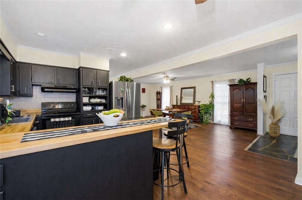 957 Rowland Road Stone Mountain, GA 30083 - Photo 10 of 36 a kitchen with stainless steel appliances a stove a sink a refrigerator white cabinets and wooden floor