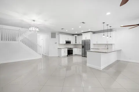 a large white kitchen with kitchen island a sink stainless steel appliances and cabinets
