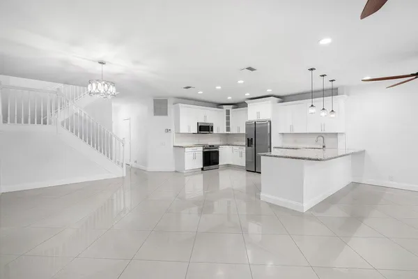 a large white kitchen with kitchen island a sink stainless steel appliances and cabinets