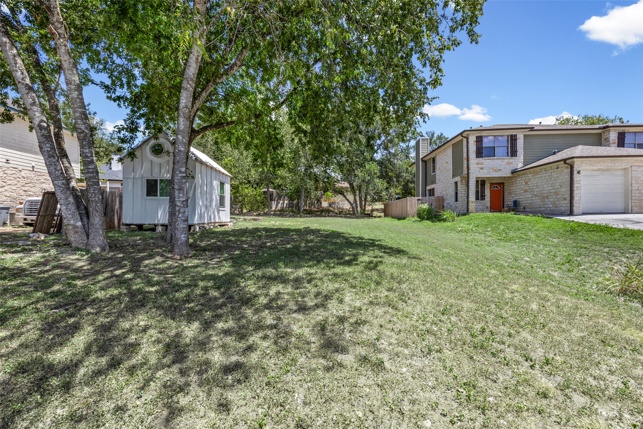5706 Spring Meadow Road Austin, TX 78744 - Photo 2 of 11 Mature shade trees frame a spacious grassy lawn beside the main home and detached outbuilding.