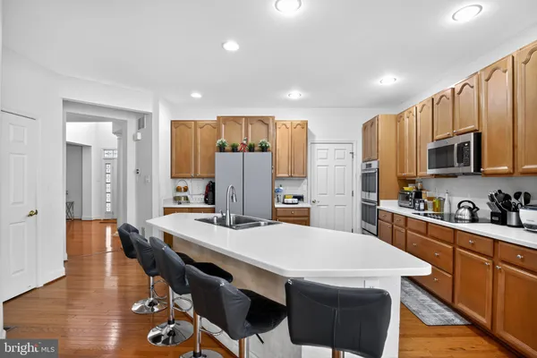a kitchen with stainless steel appliances a dining table chairs stove refrigerator and cabinets