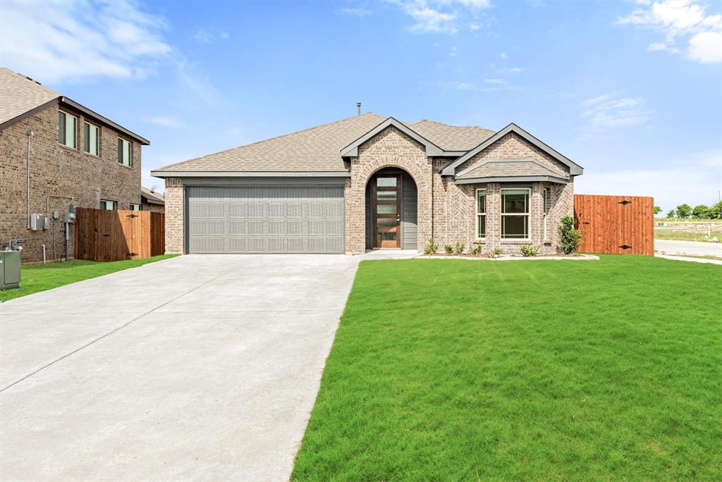 Brick-clad single-story residence featuring an arched entry, a bay window, a two-car garage, and a concrete driveway