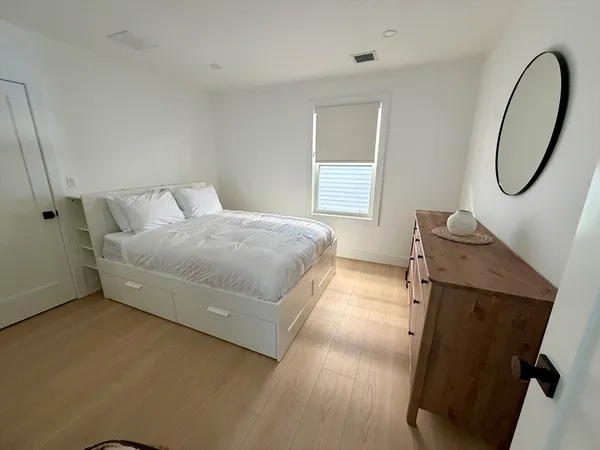a spacious bedroom with a bed mirror and window