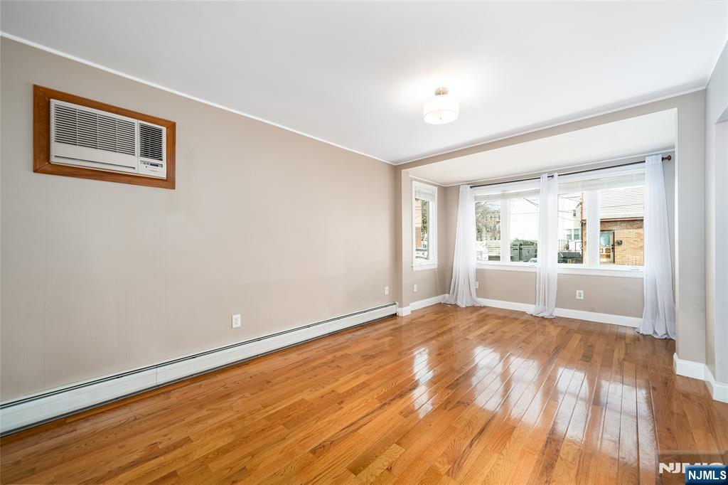 46 East 16th Street Bayonne, NJ 07002 - Photo 4 of 24 a view of an empty room with a window and wooden floor