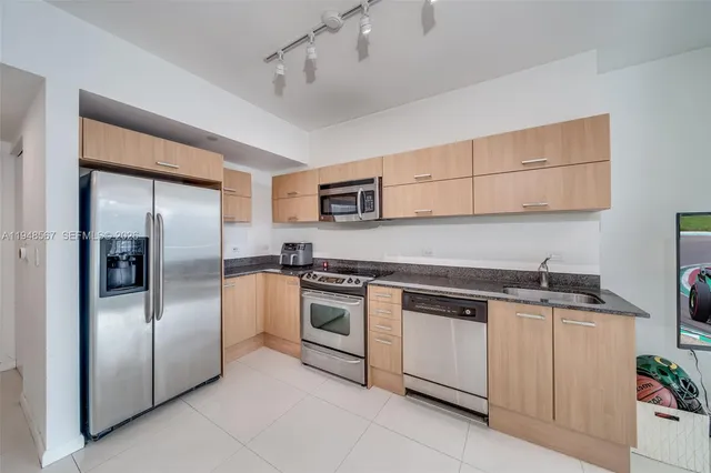 a kitchen with stainless steel appliances granite countertop a refrigerator a stove a sink and a microwave