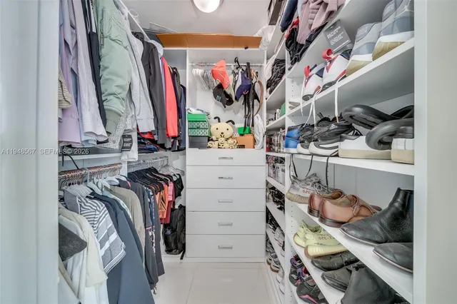 a view of walk in closet with clothes and shoes