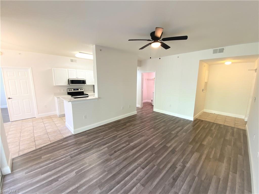 7960 Preserve Circle, Unit 616 Naples, FL 34119 - Photo 4 of 20 a view of a kitchen with wooden floor a ceiling fan and stainless steel appliances