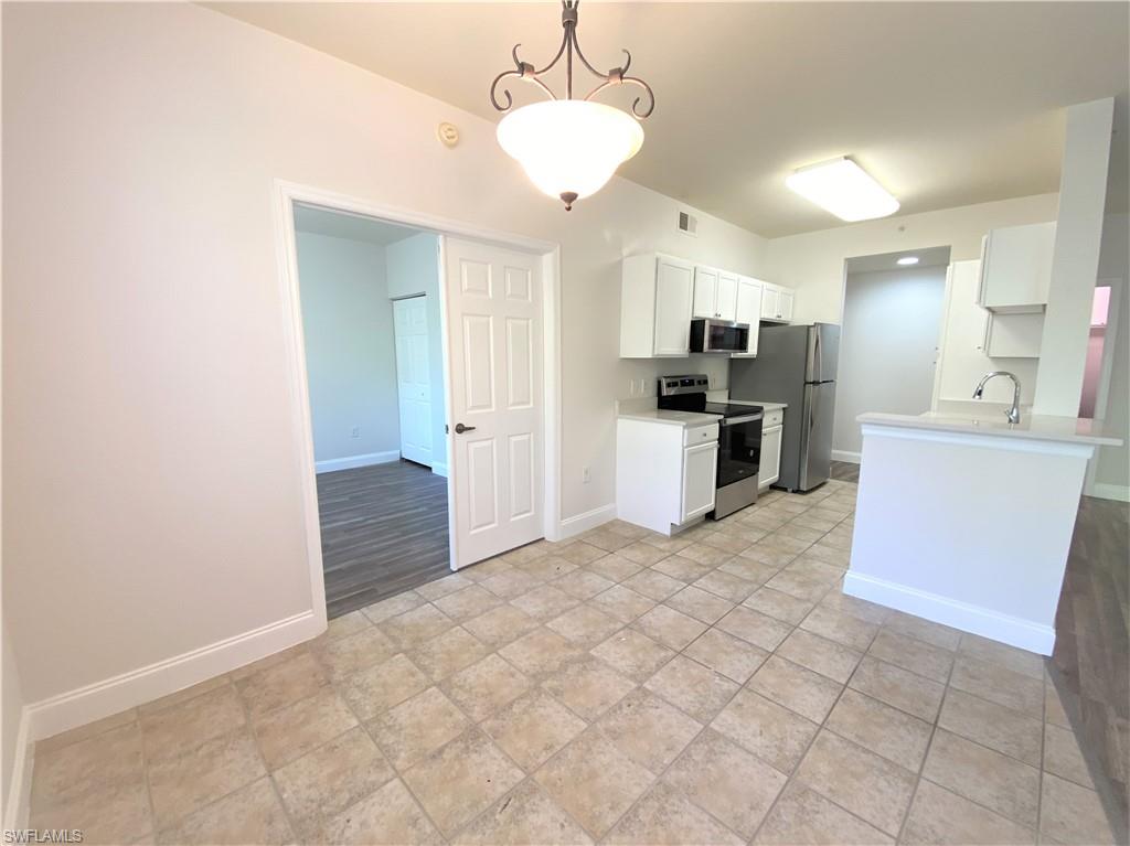 7960 Preserve Circle, Unit 616 Naples, FL 34119 - Photo 7 of 20 a kitchen with kitchen island a sink cabinets and stainless steel appliances