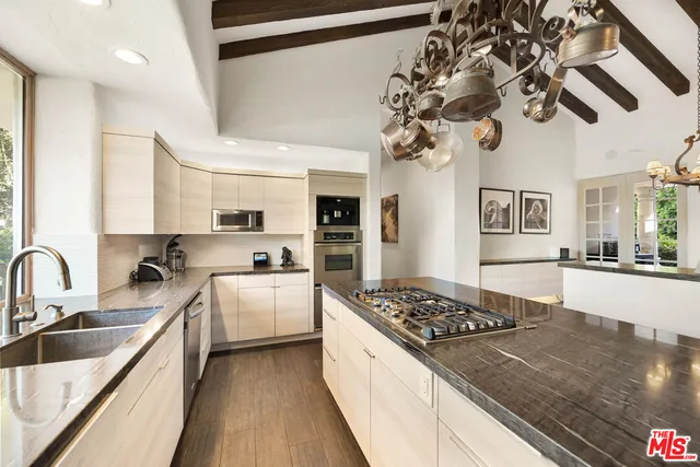 a kitchen with stainless steel appliances granite countertop a sink a refrigerator and wooden floor