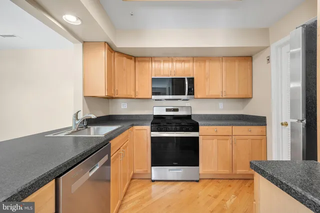 a kitchen with stainless steel appliances granite countertop a stove a sink and a microwave