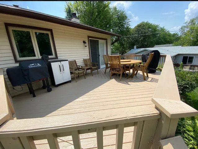 a view of a patio with table and chairs with wooden floor and fence