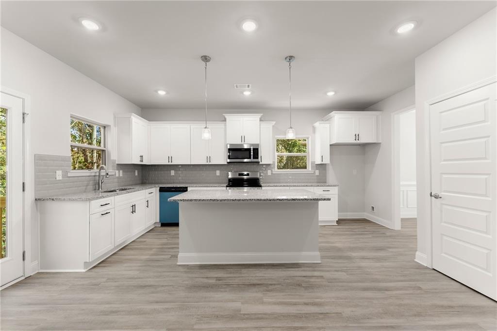 661 Forest Way Cornelia, GA 30531 - Photo 12 of 45 a large kitchen with kitchen island a sink a center island stainless steel appliances and a window