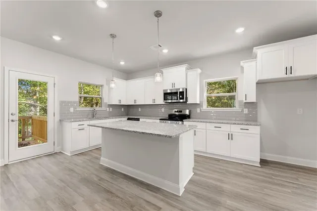 a kitchen with appliances a sink a window and cabinets