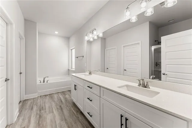 a bathroom with a double vanity sink a mirror and a bathtub