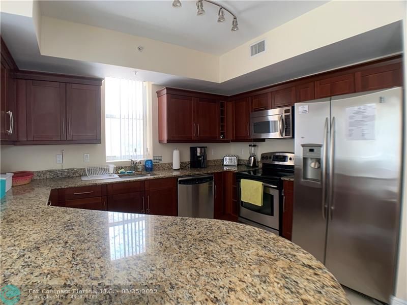 a kitchen with granite countertop a refrigerator sink and cabinets